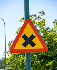 A triangular caution sign is prominently displayed in an urban environment, alerting drivers of...