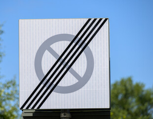 Bright day features a sign displaying a no entry symbol crossed by diagonal stripes. The background...