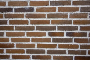 Close-up view of a brick wall displaying a variety of brown tones and textures. The wall creates an...