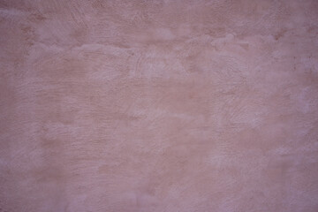 A smooth wall features a subtle pink hue, illuminated by natural light, creating a warm ambiance....