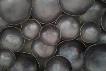 Abstract close-up of clustered metallic black ceramic bowls with subtle sheen and organic contours....
