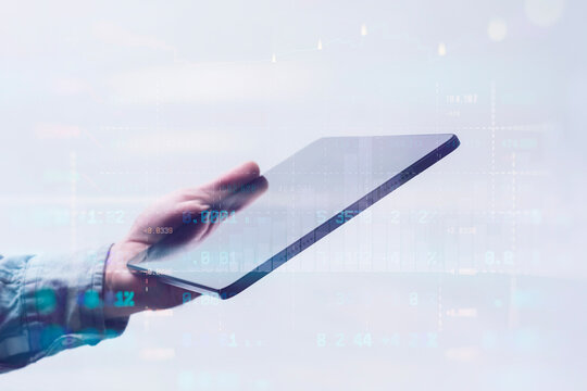 Close-up of a man in a shirt using a tablet with digital stock market data and financial graphs. Concept modern financial technology, online trading and digital analytics.