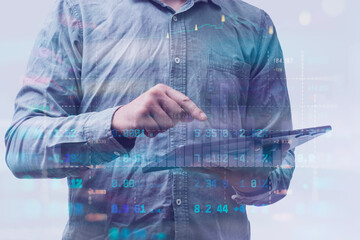Close-up of a man in a shirt using a tablet with digital stock market data and financial graphs....