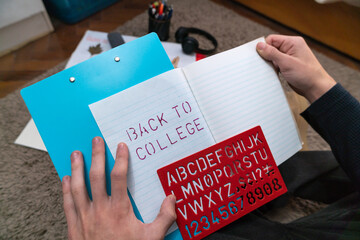 Student writing back to college on a notebook using a stencil.