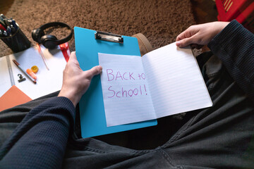 Teenager writing in notebook while sitting on floor at home, copy space.