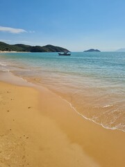 Búzios beaches (Praia do Canto) serene winter afternoon, golden sand beach with crystal-clear waters and a bright blue sky. Small boats gently float on the calm sea, creating a peaceful idyllic scene.