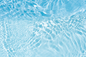 Blue water with ripples on the surface. Defocus blurred transparent blue colored clear calm water surface texture with splashes and bubbles. Water waves with shining pattern texture background.