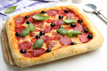 Tasty homemade pizza and cutter on white table, closeup