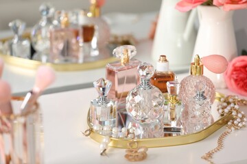 Bottles of different perfumes and accessories on dressing table indoors, closeup