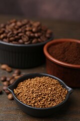Different types of instant coffee and beans in bowls on wooden table against brown background, closeup