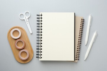 Notebooks, decorative craft tapes, scissors and pens on gray background, flat lay