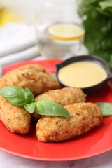 Tasty fried croquettes, basil and sauce on white marble table, closeup