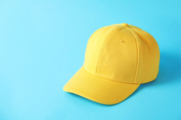 Yellow baseball hat on light blue background, space for text