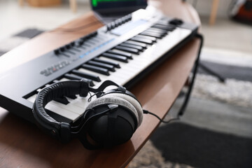 Headphones and MIDI keyboard on wooden table indoors, selective focus
