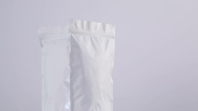Zipper stand-up pouches spinning on light grey background, closeup. Space for text