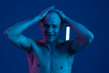 A distressed man expressing intense emotions against a dark blue background with vibrant lighting....