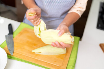 Chef preparing peruvian ceviche, carefully removing corn husk in kitchen