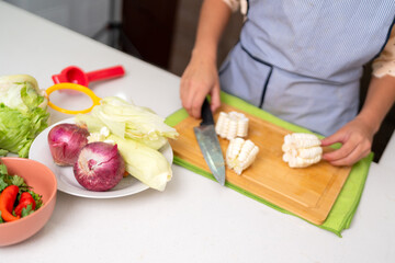 Chef preparing peruvian ceviche, chopping corn on the cob in a modern kitchen
