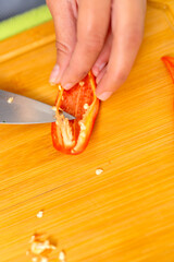 Chef removing seeds from a red chili pepper on a wooden cutting board