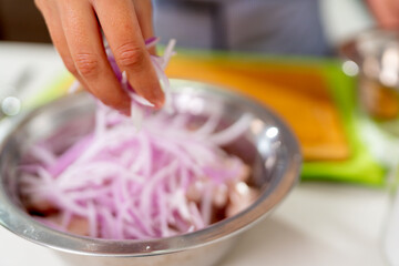 Chef adding red onions to marinating fish for peruvian ceviche