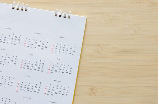 close up top view on white calendar 12 month to make schedule and appointment meeting or manage timetable each day lay on wood table background for planning work and life concept