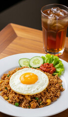 Indonesian meal featuring fried rice, fried egg, and veggies