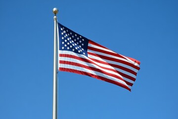 Obraz premium American flag waving proudly against clear blue sky symbolizing freedom and patriotism, ideal for national pride, celebration, and independence themes