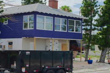 Residential Home Renovation with Vibrant Exterior and Construction Dumpster in Florida.Vivid blue...