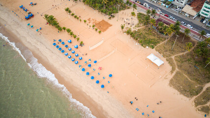 Sunny day at a sandy beach in João Pessoa, Paraíba, Brazil, with blue umbrellas, palm trees and...