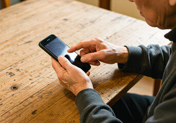 テーブルでスマホを操作するシニア世代の男性
