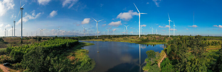 Aerial view of powerful Wind turbine farm for energy production on beautiful cloudy sky at highland. Wind power turbines generating clean renewable energy for sustainable development green energy.