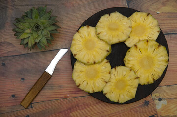 Pineapple juicy yellow slices wooden background. Top view. Pineapple fruit cut on wooden. Chopped...