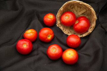closeup of a red tomato isolated on a black studio background, Tomato isolated. Tomatoes on black background. cherry tomatoes in a wooden bowl isolated.