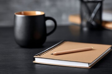 Brown Notebook and Pencil on Dark Desk with Black Mug