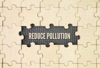 Wooden puzzle with the word reduce pollution. taking actions to decrease the amount of harmful...