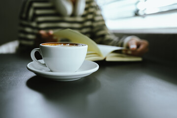 Young Asian woman making latte in a relaxed atmosphere with laptop and notebook and notepad while combining work and relaxation during a quiet coffee break at home or office.
