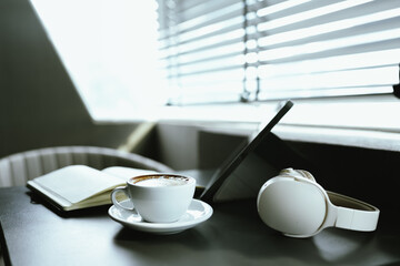 Young Asian woman making latte in a relaxed atmosphere with laptop and notebook and notepad while combining work and relaxation during a quiet coffee break at home or office.
