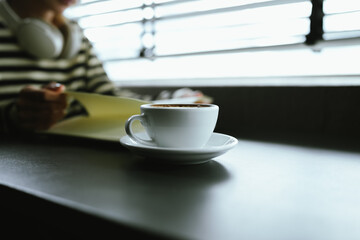 Young Asian woman making latte in a relaxed atmosphere with laptop and notebook and notepad while combining work and relaxation during a quiet coffee break at home or office.