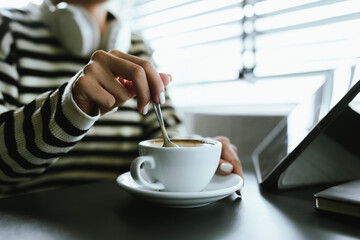 Close-up of a woman holding a glass of latte to create warmth, comfort and calmness during a quiet morning coffee break at home or at work.