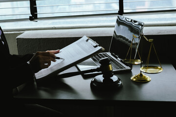 Obraz premium A gavel rests on a legal desk with blurred background of a professional signing documents, symbolizing justice, legal process, court authority, and formal legal consultation setting.