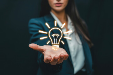 Businesswoman presents a glowing lightbulb symbolizing innovation and new ideas