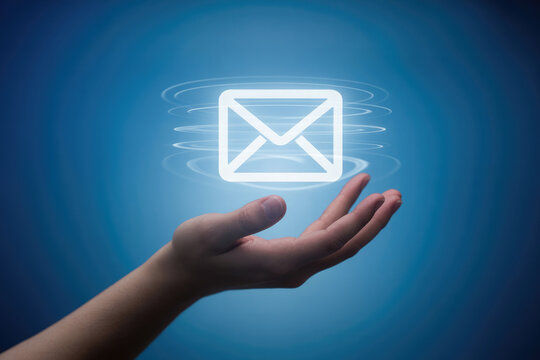 Hand holding a glowing email icon with digital waves on a blue background
