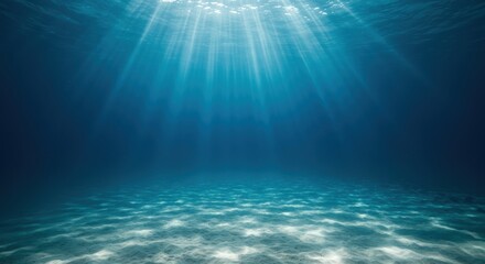 Tranquil underwater scene displaying sun rays penetrating the deep blue ocean waters and illuminating the sandy seabed