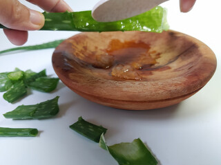 Scooping out the aloe vera gel using spoon into wooden plate