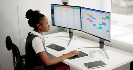 African American Woman Overseeing Project Calendar On Computer Screen