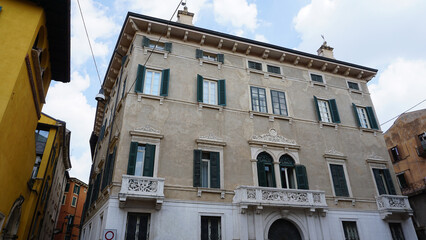 Beautiful traditional Italian building with flowers on balcony of medieval wall, Verona, Italy