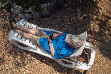 Relaxed Senior Man Lounging Outdoors on a Sunny Day in Casual Attire