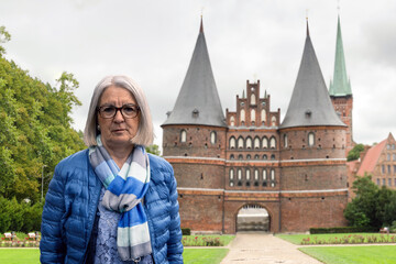 Senior Woman Posing in Front of Historic Landmark with Brick Architecture