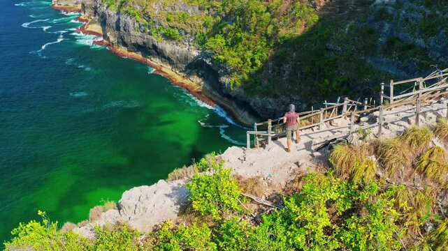 Travel people explore Bali famous landmark and popular travel destination Kelingking beach, Nusa Penida, Bali, Indonesia 4K Aerial view