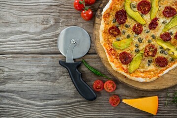 Pizza on by cutter on wooden table
